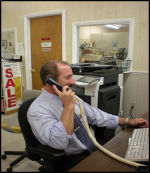 Steve Melone sitting at desk, on telephone