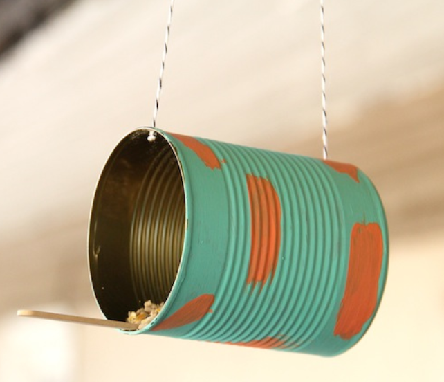 Birdfeeder made from a tin can painted green and orange. The can is hanging by twine.