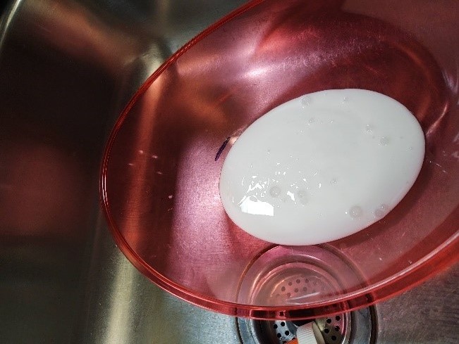 White glue in a red plastic bowl in a sink.